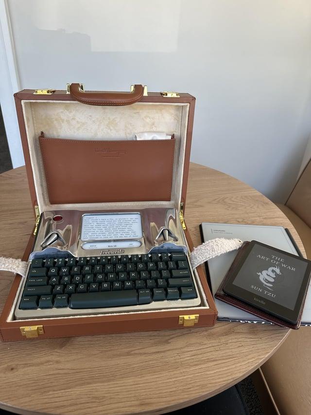 Teclado y ereader empotrados en un maletín de cuero marrón.